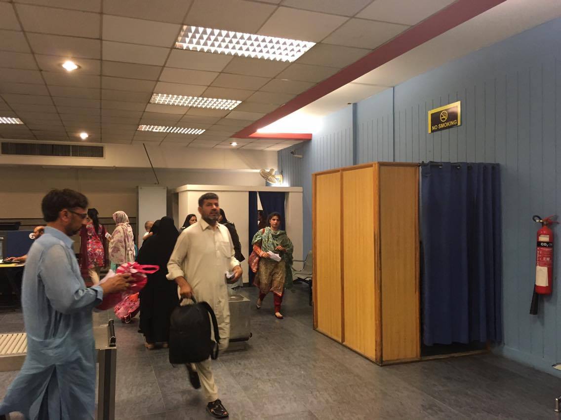 At Islamabad airport, women wearing niqab or burqa use the small rooms to the right and background of this photo for identification and security screening.