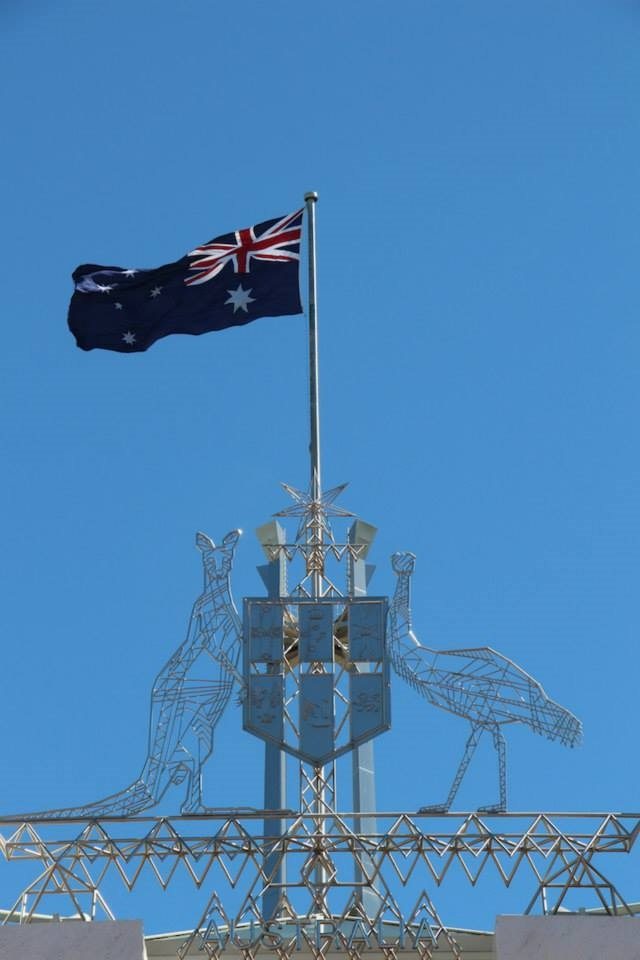 The coat of arms and flag atop Parliament House